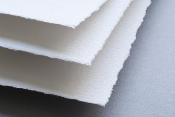 Mehrere übereinanderliegende weiße Papierblätter mit rauen, gezackten Kanten
