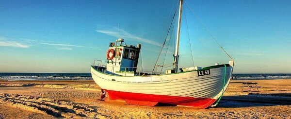Fischerboot mit der Nummer LK 49 liegt am Strand bei klarem Himmel