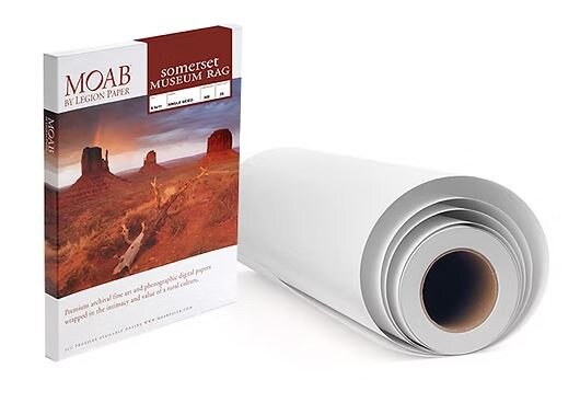 Eine Rolle Fotopapier und eine Schachtel MOAB Papier mit einer weiläufigen Landschaft auf dem Etikett